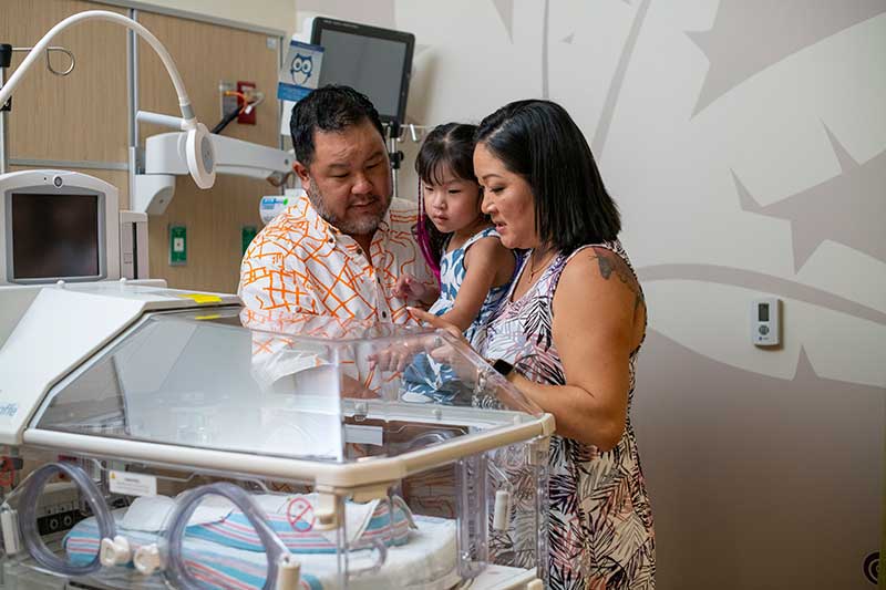 The Yee family looks at an incubator.