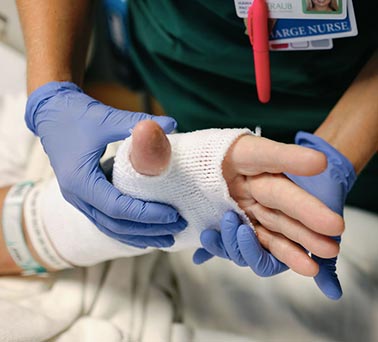 Bandaged hand of Burn Unit patient gently held by nurse