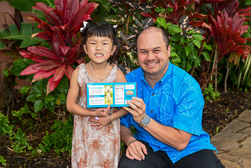 Kalley-Mae shows off the new Diamond Bakery soda cracker box with Butch Galdeira, Diamond Bakery president.