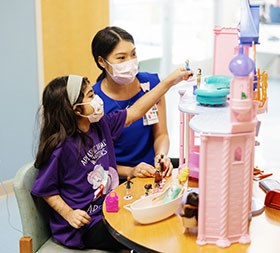 child life specialist with a little girl in the hospital playroom